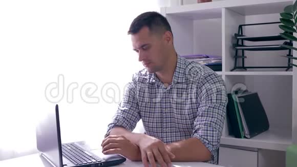 疲倦的商人坐在办公室的桌子上在他的笔记本电脑屏幕上听到非常坏的消息视频的预览图