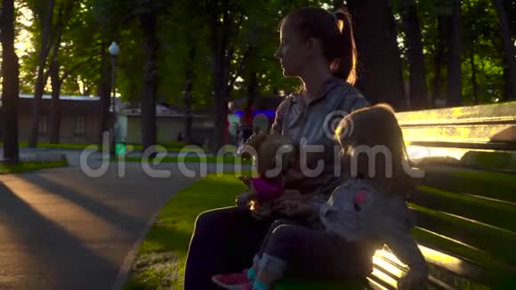 女孩和母亲坐在公园的长凳上视频的预览图