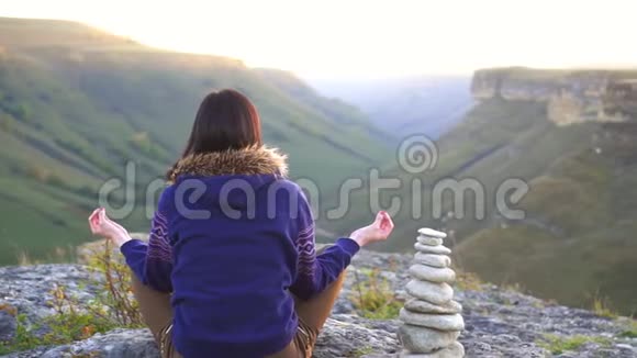 日落时坐在山顶莲花状的女孩后视图视频的预览图