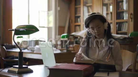 年轻的女学生律师正在看书在坐在图书馆的笔记本电脑上打字视频的预览图