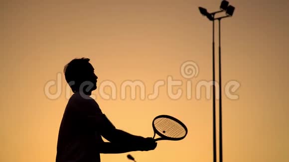 健康的生活方式和积极的休息打大网球运动员站在橙色日落的背景上手持一个视频的预览图