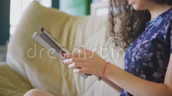 漂亮的年轻女子在数码平板电脑上滚动视频的预览图