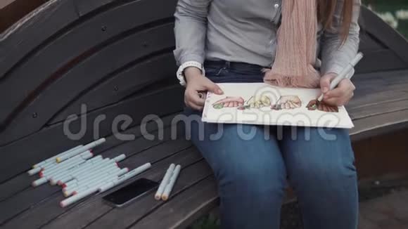 一个坐在长凳上的女人她的双手特写镜头在一张专辑中画了记号视频的预览图