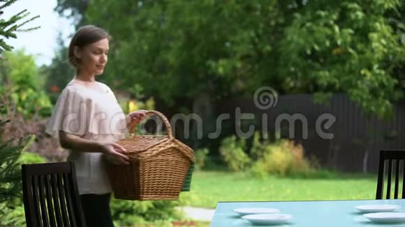 微笑的女士把篮子放在桌子上家庭晚餐在户外野餐准备视频的预览图