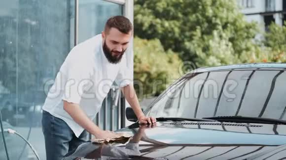 有胡子的男人在洗车场用布洗车视频的预览图