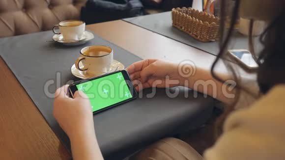 在咖啡厅使用绿色触摸屏手机的Swoman视频的预览图
