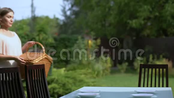 女性在桌上摆放柳条野餐篮在乡间别墅户外野餐视频的预览图