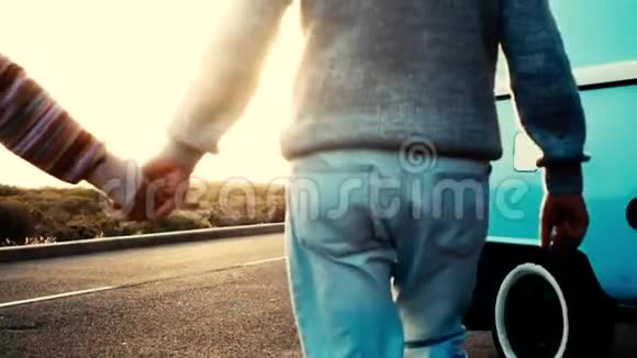 成年的成熟夫妇在背光和背景的夕阳下的街道上牵着爱和浪漫的手永远视频的预览图