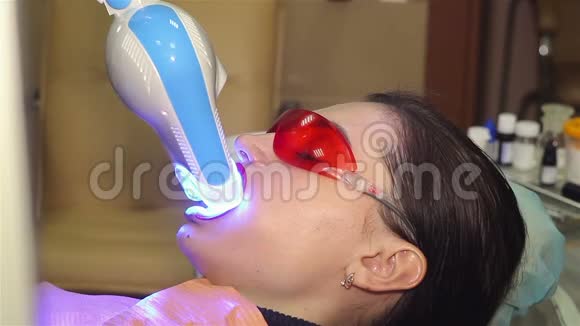 年轻女子在牙科医生办公室用紫外线机器进行紫外线美白视频的预览图