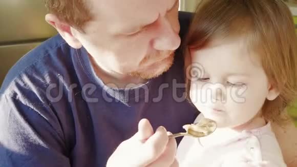 愁眉苦脸的男人用勺子喂小女孩视频的预览图