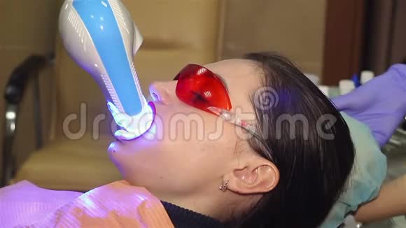 年轻女子在牙科医生办公室用紫外线机器进行紫外线美白视频的预览图