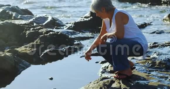坐在4k附近岩石上的老妇人视频的预览图