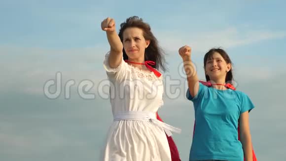 妈妈和女儿穿着红色斗篷扮演超级英雄幸福的家庭扮演超级英雄妈妈和孩子穿上红色的斗篷视频的预览图