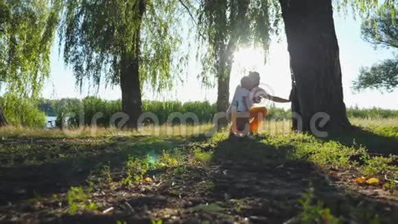 在阳光明媚的夏天小爸爸和他的孩子在树干上找窝洞快乐的家庭花时间视频的预览图