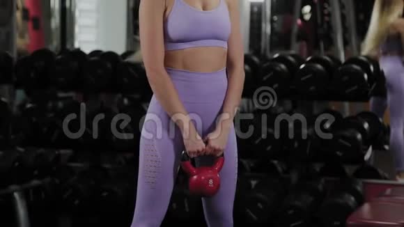 有着美丽身材的运动女人正在健身房里用水壶铃训练视频的预览图