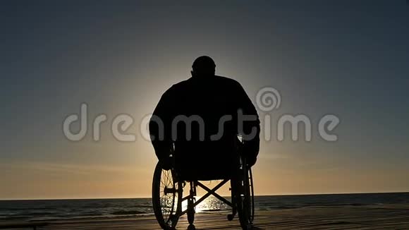 坐轮椅的人靠近海平面视频的预览图