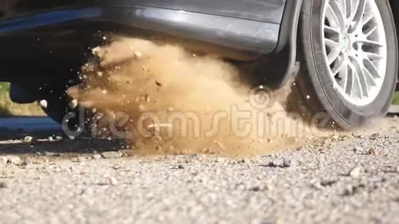 汽车车轮在运动开始时在沥青路上打滑小石头和泥土从轮胎下面飞出来视频的预览图