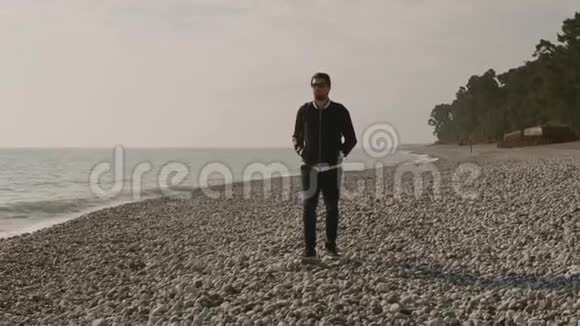 一个孤独的人漫步在石滩上海浪拍打着海岸视频的预览图