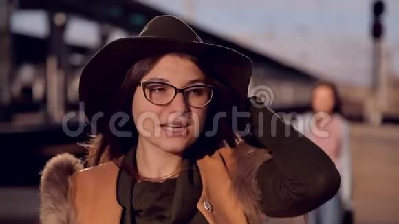 戴着眼镜和帽子的女孩在火车站等火车后面有个女孩问视频的预览图