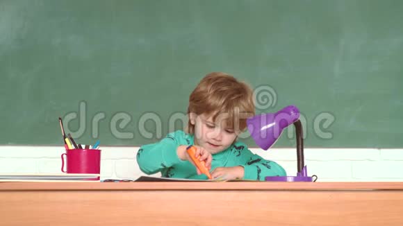 有趣的小男孩指着黑板学校的孩子开朗微笑的孩子在黑板前教育小可爱视频的预览图