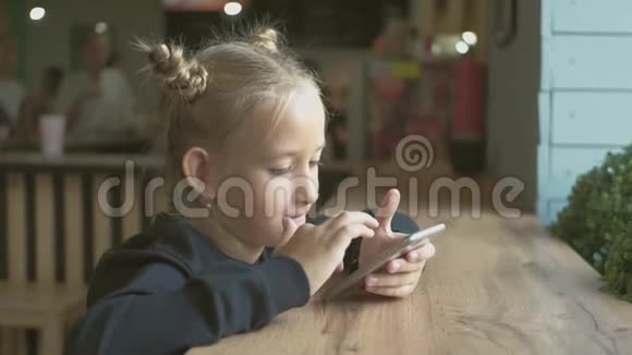快乐的女孩看起来很聪明小女孩玩手机教育学校技术和互联网概念视频的预览图
