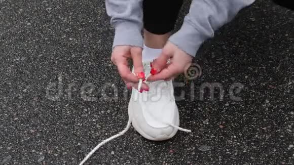 年轻迷人的白种人女孩在冬天在雪地公园跑步前系鞋带近距离射击视频的预览图