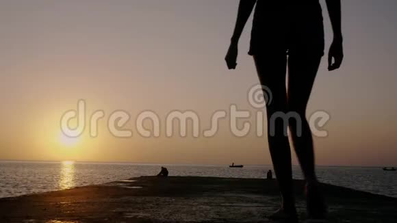 日出时沿着码头走的年轻女子视频的预览图