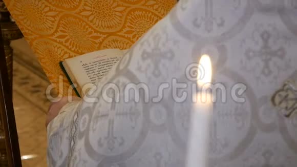 一位牧师的祈祷背景下东正教教堂里的白色燃烧蜡烛发出啁啾声视频的预览图