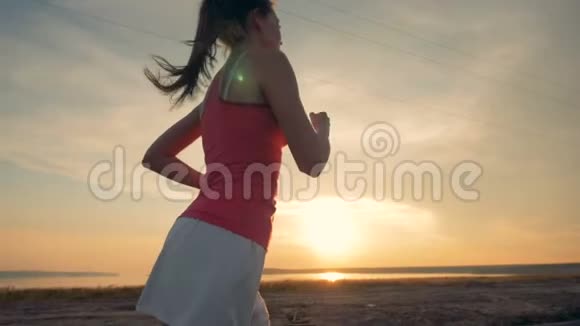 日落时一个年轻迷人的女人跑步的侧视健康的生活方式观念视频的预览图