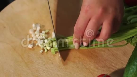 一位女厨师的特写在木板上切葱视频的预览图
