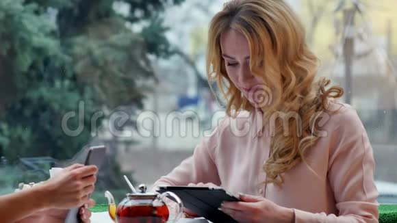 年轻漂亮的快乐女人在咖啡馆里用平板电脑视频的预览图