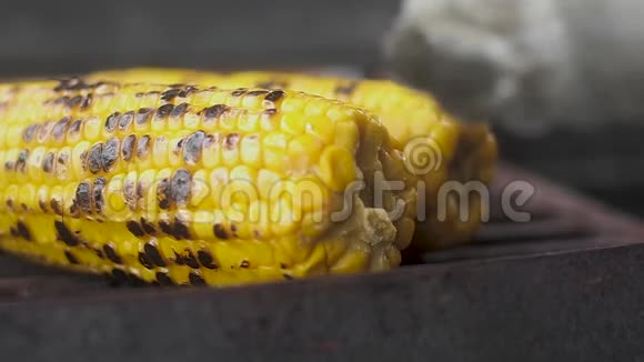 厨师钳在烤架上翻炒多汁的甜玉米特写慢动作视频的预览图