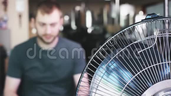 年轻人在工作时打开冷却风扇夏季炎热主题视频的预览图