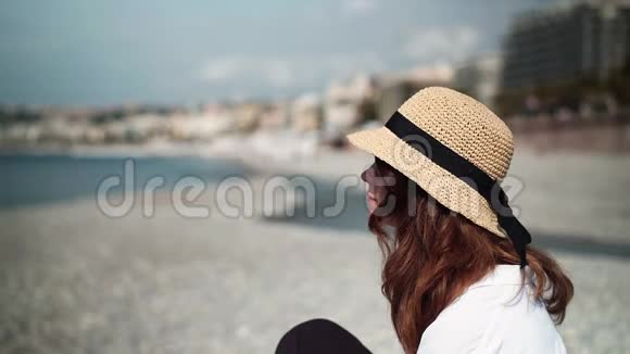 在鹅卵石海滩上看大海的女人视频的预览图