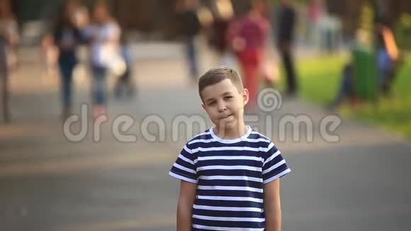 一个穿条纹T恤的小男孩在微笑和欢呼春天晴朗的天气视频的预览图