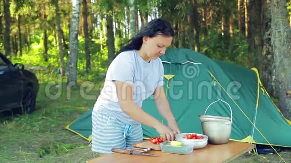 一个年轻的女人正在把樱桃番茄放在沙拉碗里野餐视频的预览图