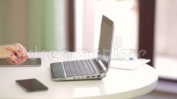 一名女学生正在咖啡馆里的笔记本电脑上工作并在平板电脑上浏览图片右起全景视频的预览图