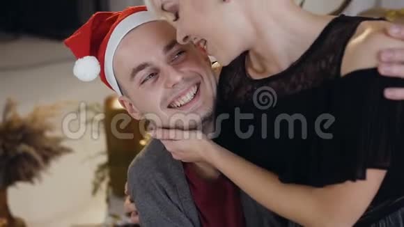 圣诞夜或新年时戴着圣诞帽的帅哥在爱情中拥抱女朋友快乐的年轻情侣视频的预览图