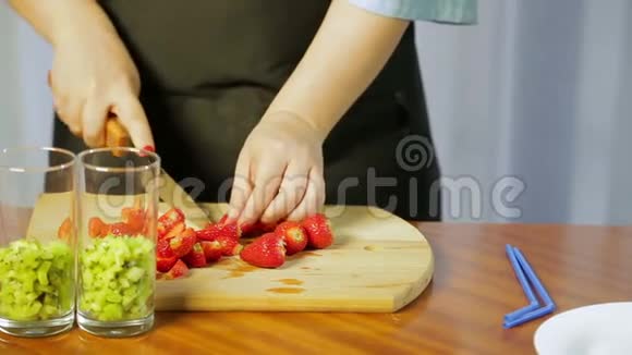一个女人用一把大刀在木板上切熟的草莓视频的预览图