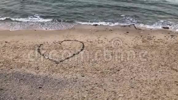 海浪冲刷成一颗由石头组成的心在一个孤独的海滩上情人节概念4k视频视频的预览图