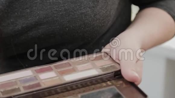 专业的化妆师女人用她手中的调色板化妆视频的预览图