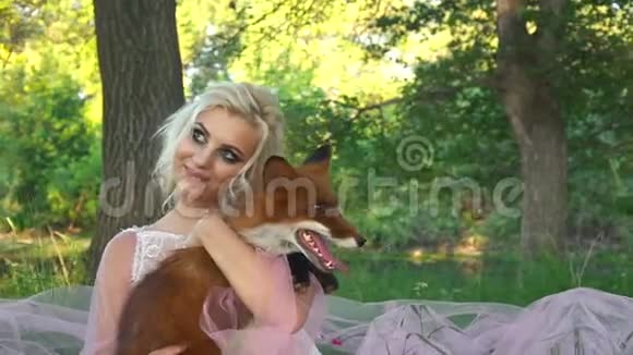 金发女郎怀里抱着一只狐狸坐在森林里视频的预览图