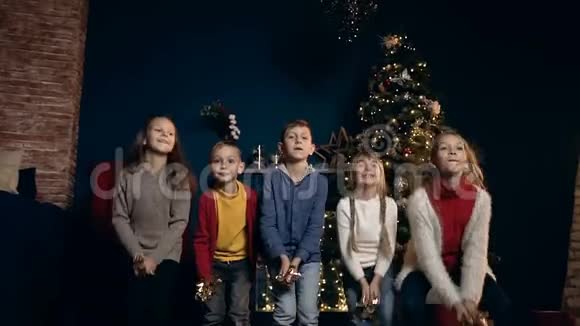 五个小孩一边笑一边把纸屑扔在基督弥撒树的背景上视频的预览图