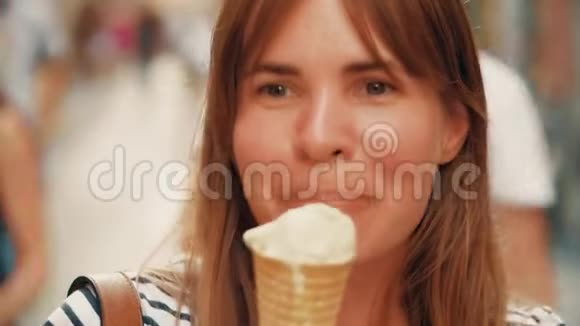 快乐的年轻女子吃着冰淇淋筒走在街上视频的预览图