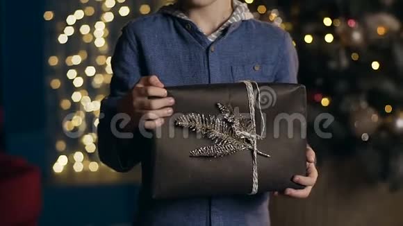 穿着蓝色衬衫的小可爱男孩手里拿着圣诞礼物视频的预览图