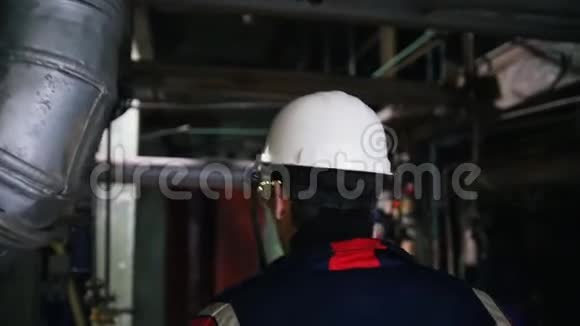 一个戴着头盔的男工程师在工厂里走来走去视频的预览图