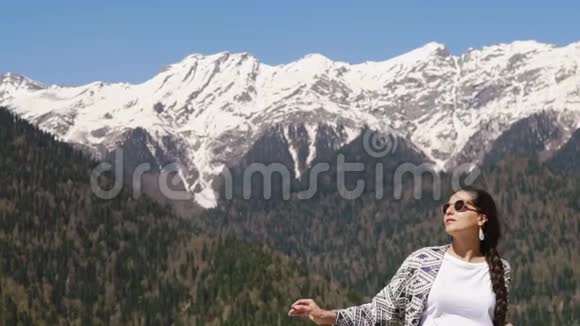 在阳光明媚的日子里放松的旅行者女人站在群山的背景下视频的预览图