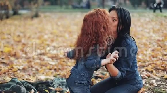 小红发女孩和妈妈一起在秋天公园度过时光他们玩拥抱玩得开心视频的预览图
