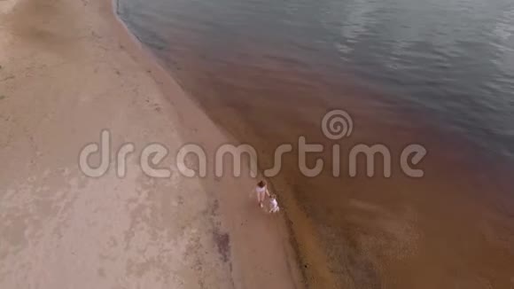 母女俩沿着沙滩沿着河跑海滩夏日阳光明媚空中射击视频的预览图