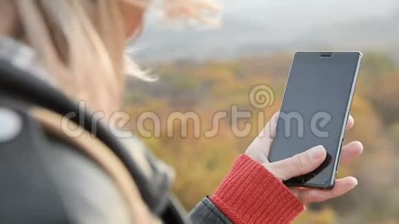 特写金发的OTS女孩手指在她的智能手机上女孩手持智能手机视频的预览图
